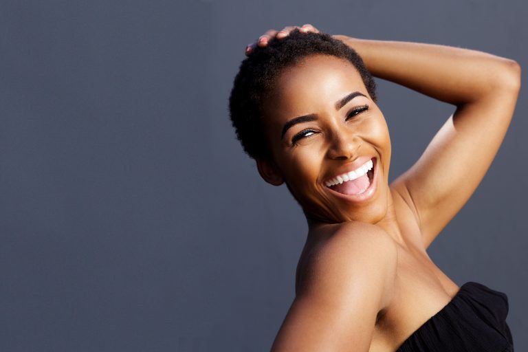 A woman smiling with her hands in her hair.